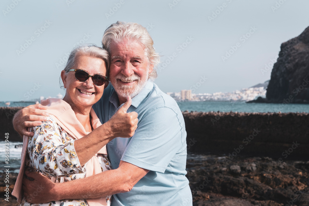 Senior happy couple in love enjoying sea excursion having fun in summer vacation embracing each other - background of  sky and sea water  - active retired elderly people and fun concept