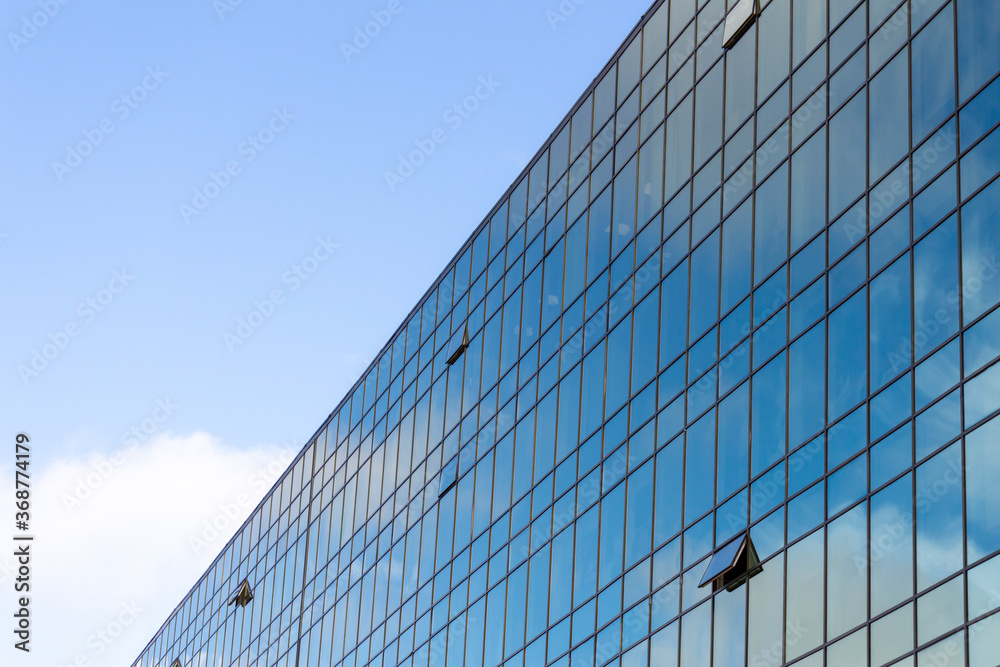 Low angle view of modern office building covered with glass. Blue sky with some white clouds in the background. Corporate Buildings Theme. Low angle view of modern office building covered with glass. Blue sky with some white clouds in the background. Corporate Buildings Theme.