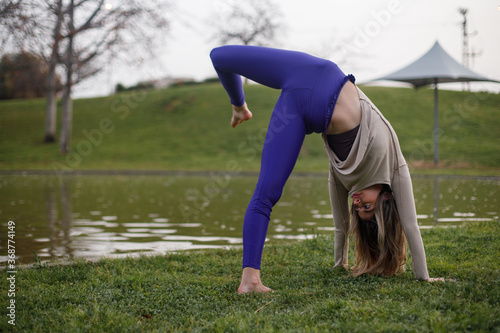 Yoga model stretching her body during a workout session at the park. Shot with natural light at sunset.