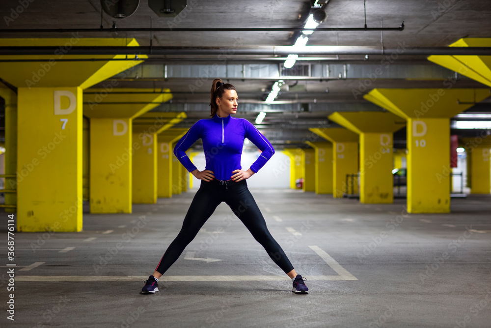 Fototapeta premium Fit girl in sportswear exercise in public garage to stay fit