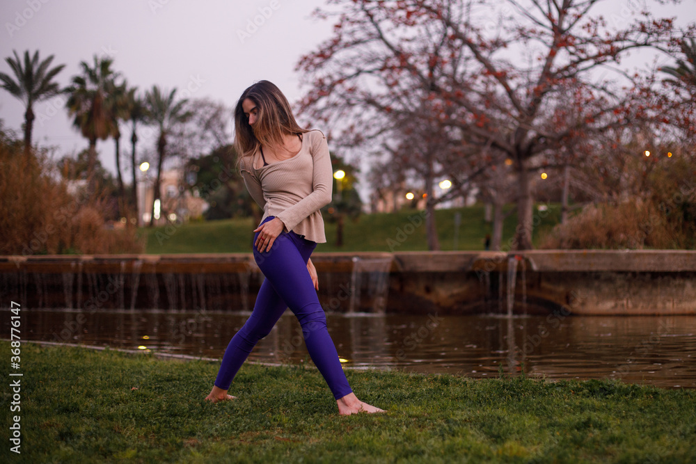 Yoga model stretching her body during a workout session at the park. Shot with natural light at sunset. Yoga model stretching her body during a workout session at the park. Shot with natural light at sunset.