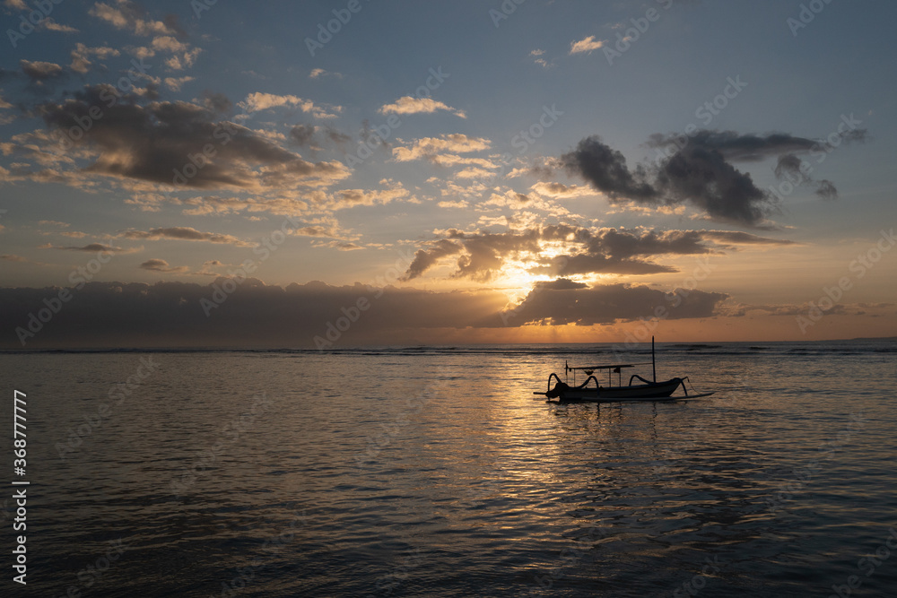 The sun's rays over the sea, burst out of the cloud. Dramatic sunset on the sea, beautiful peaceful scene, rays of light shine in water, sunbeam in cloudy sky, summer ocean view, with fisherman boat