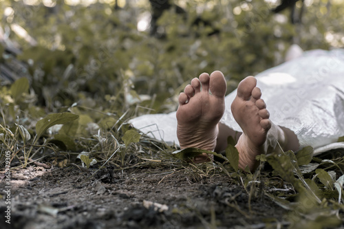 The legs of a corpse lying in the forest. Victim of a crime. Deceased person. photo