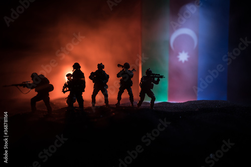 Azeri army concept. Silhouette of armed soldiers against Azerbaijani flag. Creative artwork decoration. Military silhouettes fighting scene dark toned foggy background. © zef art