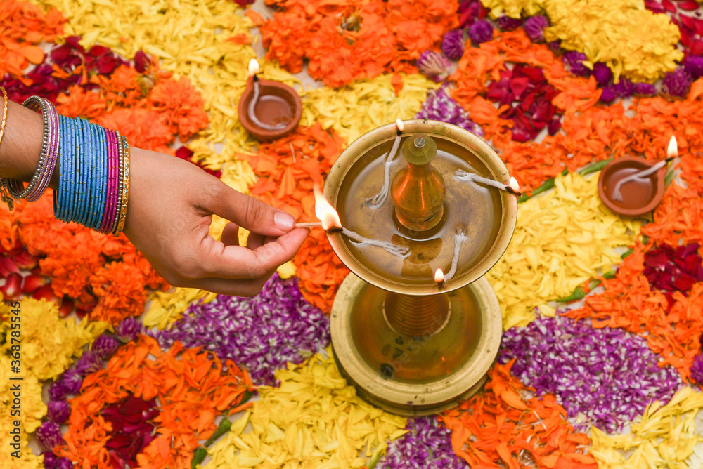 Kerala Onam festival Flower bed or Pookalam decoration, Woman lighting