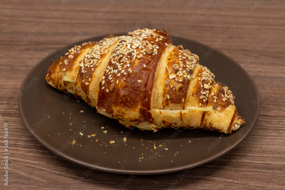 Close up view of tasty croissant sprinkled with sesame and made from puff pastry. Selective focus. Fresh pastry theme.