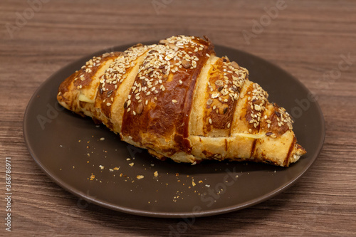 Close up view of tasty croissant sprinkled with sesame and made from puff pastry. Selective focus. Fresh pastry theme.