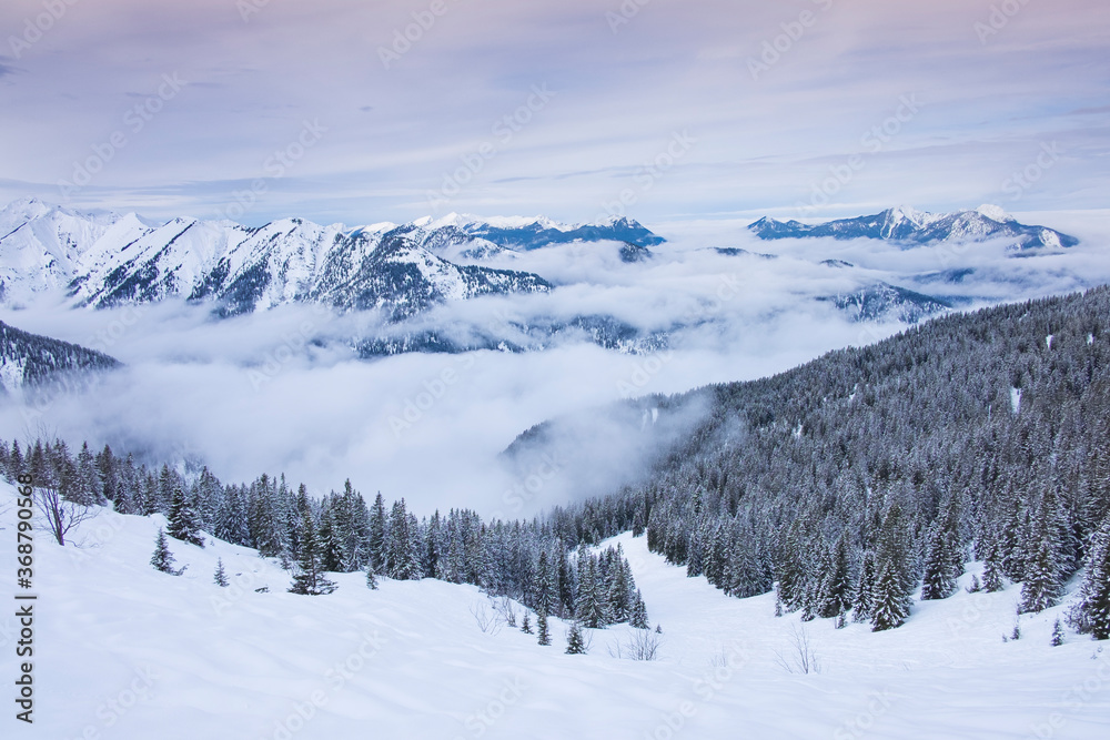 Fototapeta premium Zimowy krajobraz panoramiczny w górach Karwendel w Schafreiter, z mgłą, śniegiem i lasem.