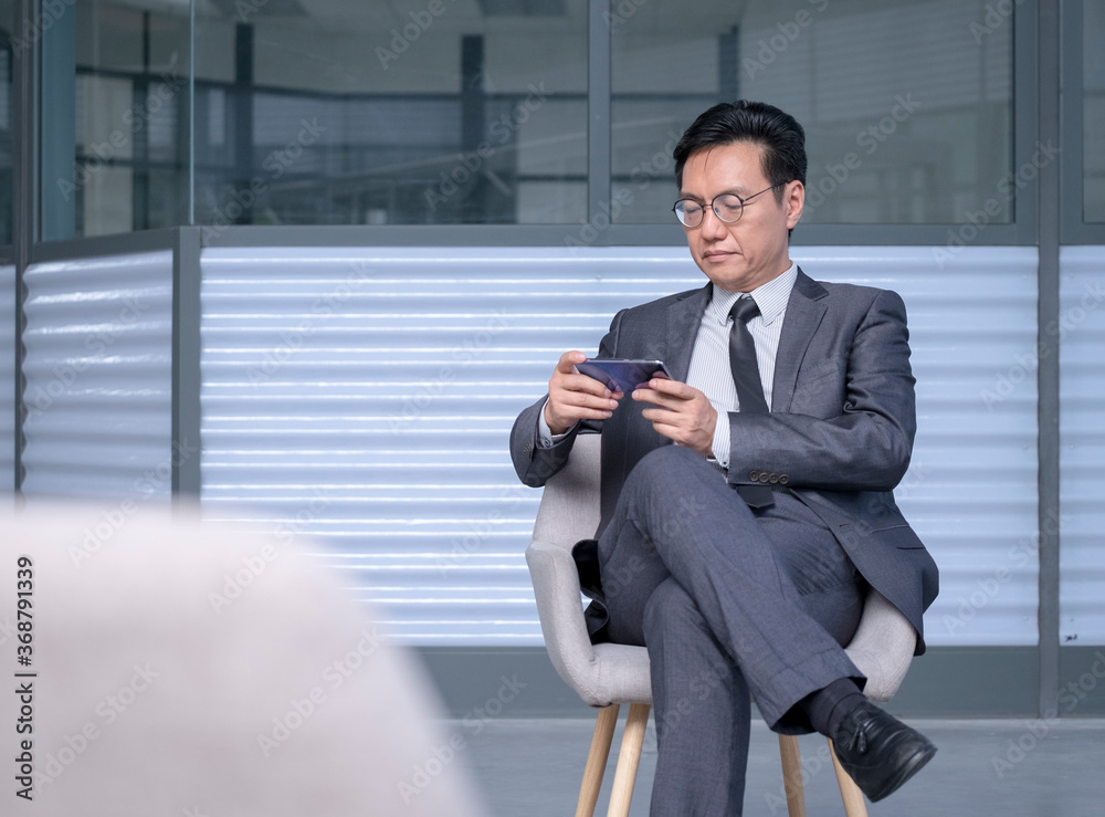 Chinese businessman using cellphone to watch live streaming or video Chinese businessman using cellphone to watch live streaming or video