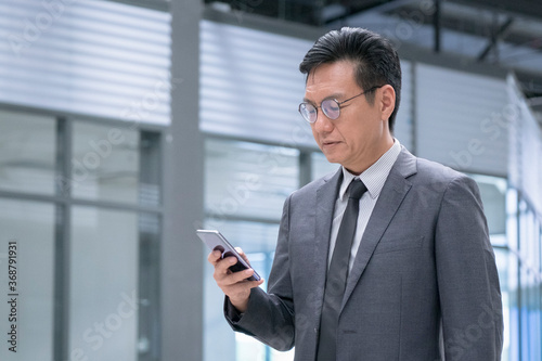 Chinese businessman in business suit and tie reading on his cellphone