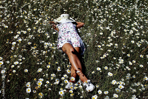 Young girl lying in the middle of daisies meadow