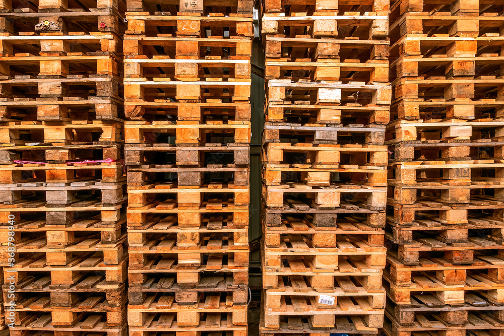 A lot stacks of used  wooden pallets of euro type on warehouse is ready for recycling. Industrial background. Close-up.