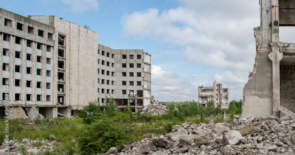 A pile of gray concrete debris against the remains of a large destroyed building. Background