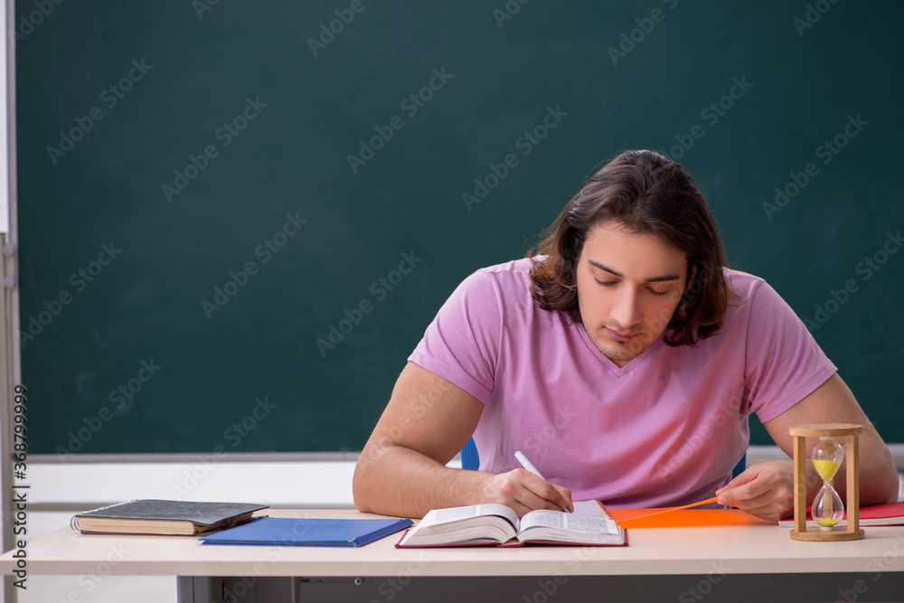 Young male student in the classroom at time management concept Young male student in the classroom at time management concept