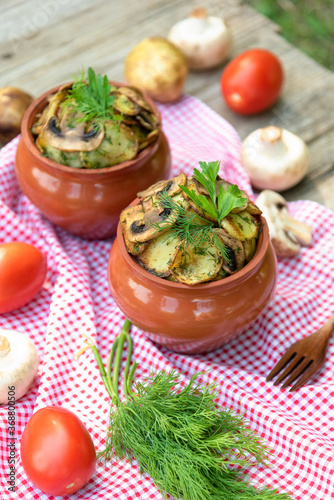 Baked potatoes with mushrooms and meat in a clay pot.