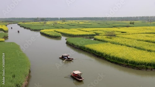 tourists enjoying boat trips along streams among rapeseed field in Duotian, Xinghua County, Nanjing, Jiangsu, China photo