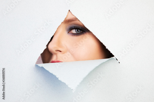 girl with makeup looks through a hole in the sheet, abstraction, background © Alla
