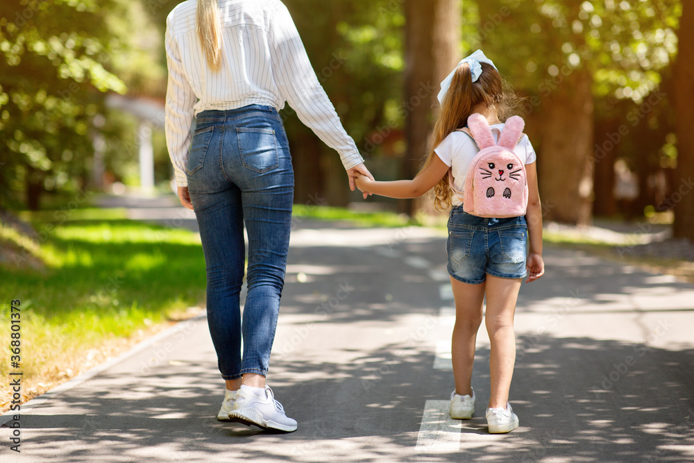 Mother And Daughter Walking Holding Hands In Park, Cropped, Back-View
