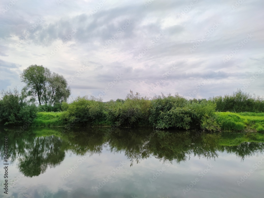 gloomy cloudy sky over green lake shore gloomy cloudy sky over green lake shore
