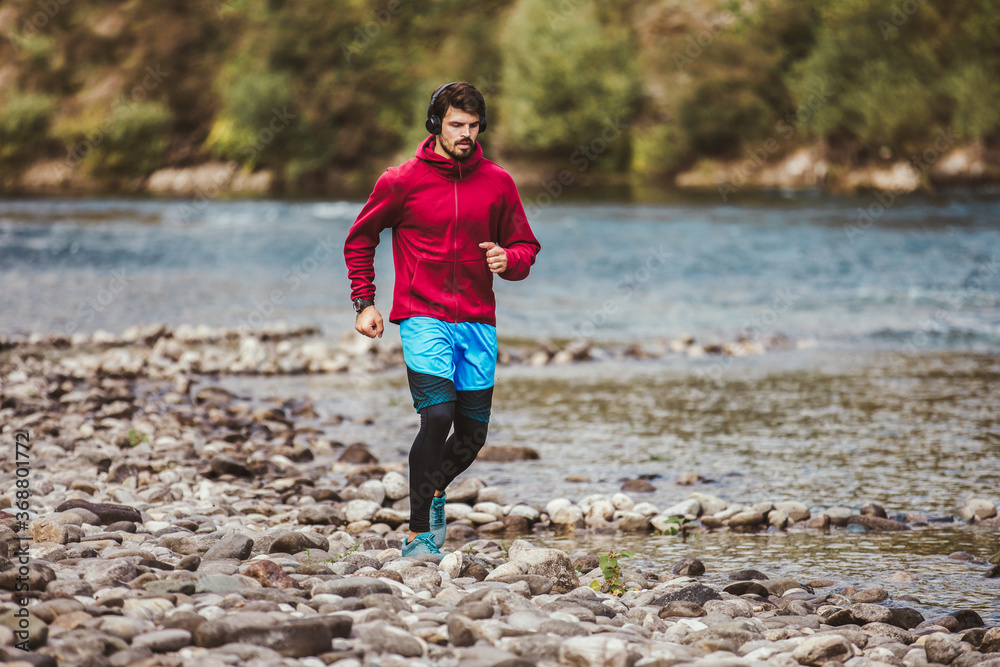 Young male athlete having a morning jogging next to the river.