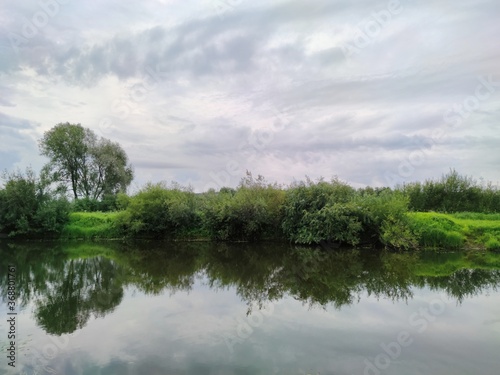 gloomy cloudy sky over green lake shore