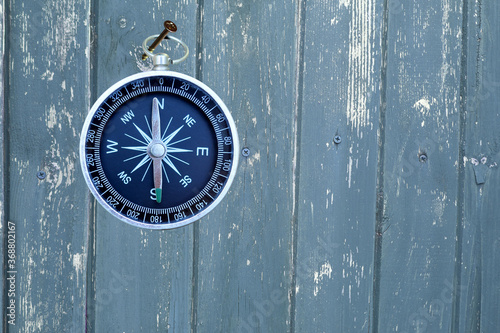 round compass on blue wooden background as symbol of tourism with compass, travel with compass and outdoor activities with compass