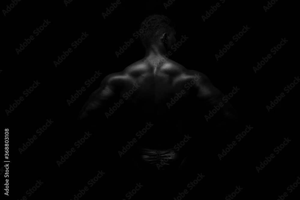 Naklejka premium Silhouette of young athlete bodybuilder man on black