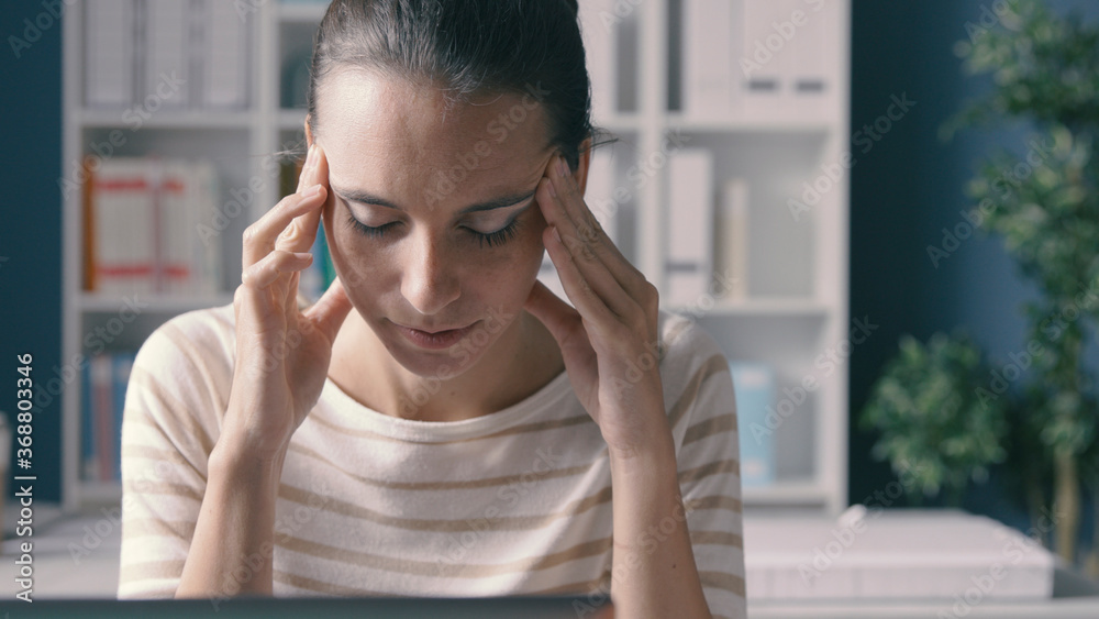 Stressed woman working in the office with headache Stressed woman working in the office with headache