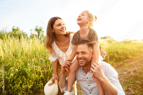 Happy parents and kid walking together in summer