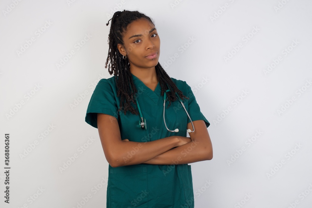 Waist up shot of beautiful self confident cheerful young doctor woman entrepreneur has broad smile, crosses arms, happy to meet with colleague, dressed in fashionable clothes. Waist up shot of beautiful self confident cheerful young doctor woman entrepreneur has broad smile, crosses arms, happy to meet with colleague, dressed in fashionable clothes.