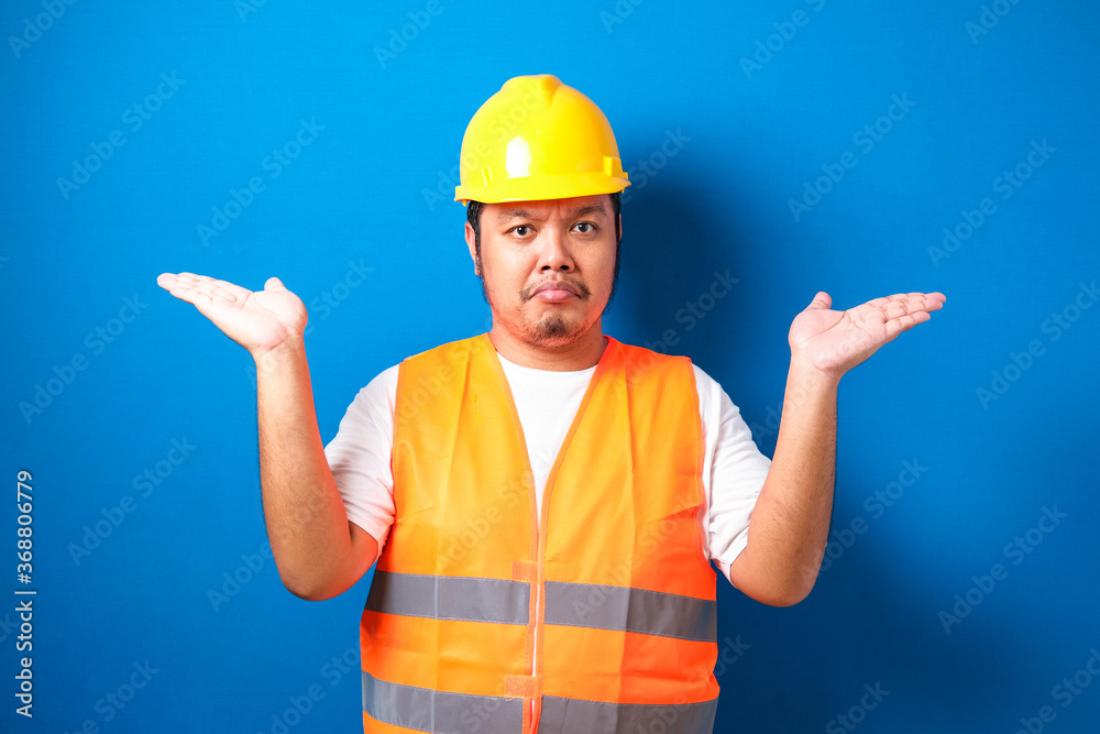 Young handsome fat asian worker man wearing orange safety vest uniform and helmet clueless and confused expression Young handsome fat asian worker man wearing orange safety vest uniform and helmet clueless and confused expression