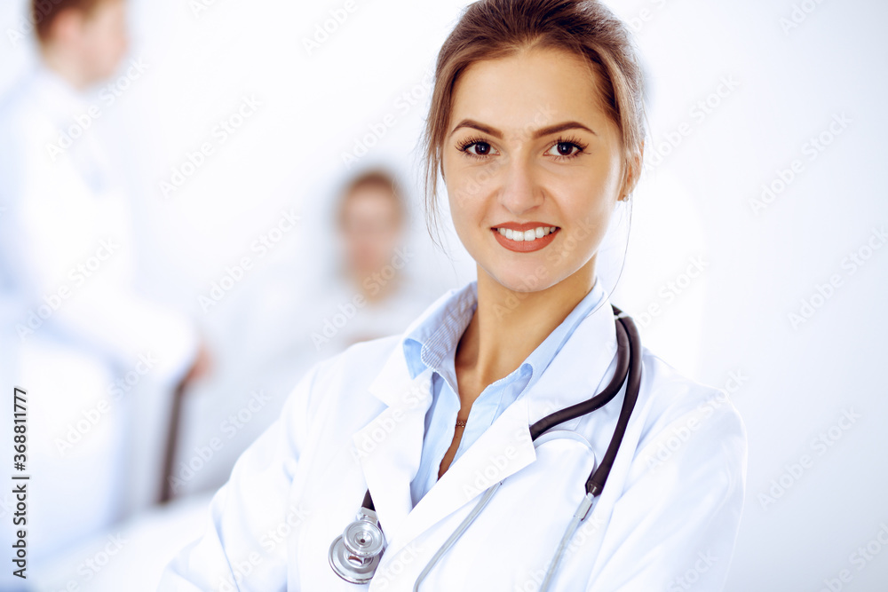 Female doctor smiling on the background with patient in the bed and two doctors Female doctor smiling on the background with patient in the bed and two doctors