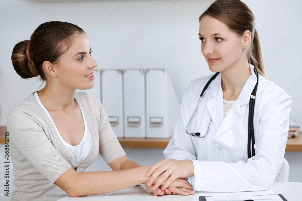Doctor and patient are sitting and discussing health examination results in clinic office. Health care, medicine and good news concepts Doctor and patient are sitting and discussing health examination results in clinic office. Health care, medicine and good news concepts