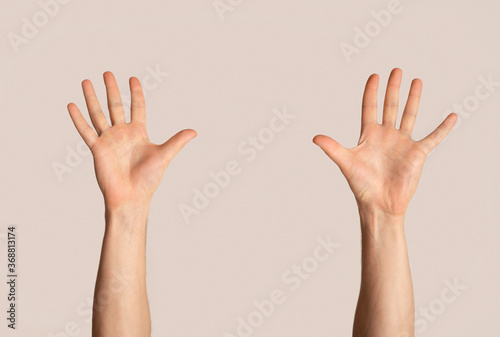 Millennial man raising both hands up on light background, closeup