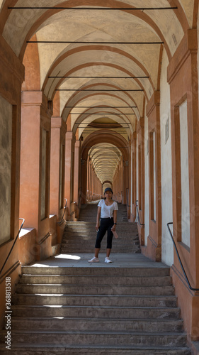 Asian woman in hat and sneakers standing in the middle of a stairway in a portico © David