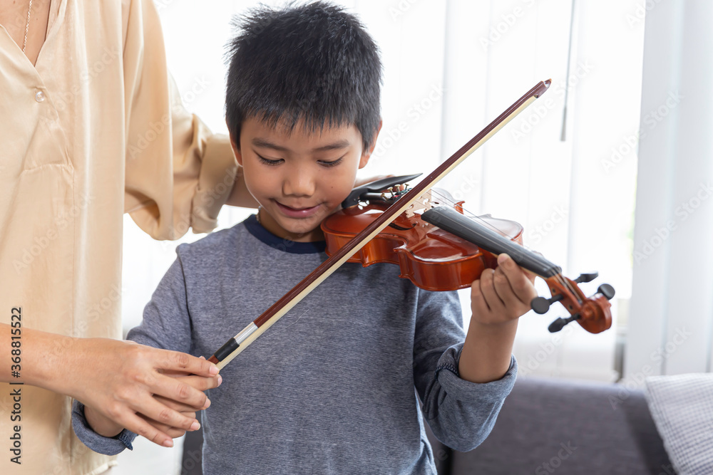 Little asia children sit on the sofa,intend to try practic and play music with violin in music class at school,prepare show in party.