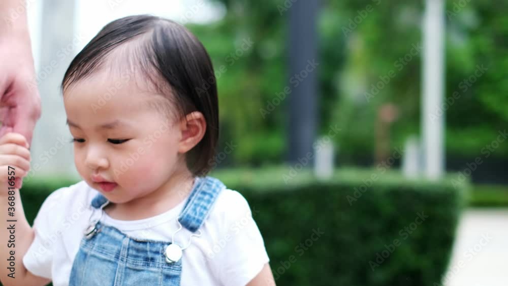 Slow motion of 1 year old cute toddler Asian boy kid in bib jeans holding mother hand and walking together..Asian mother holding hand of little with backpack outdoors, Slow motion of 1 year old cute toddler Asian boy kid in bib jeans holding mother hand and walking together..Asian mother holding hand of little with backpack outdoors,