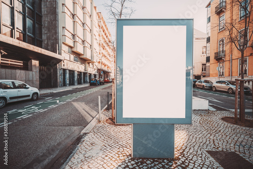 A vertical outdoor blank banner mockup in urban settings near the road  an empty street advertising poster template placeholder on a paving-stone in a residential district on a sunny day