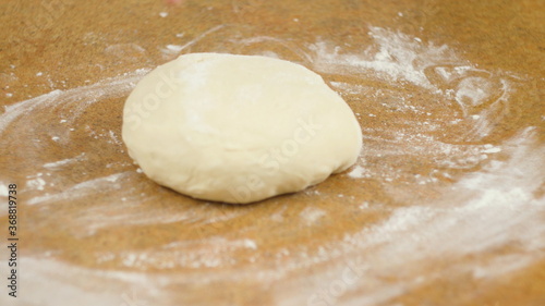 The woman or man on the table roll out the dough for cookies, pizza, pasta