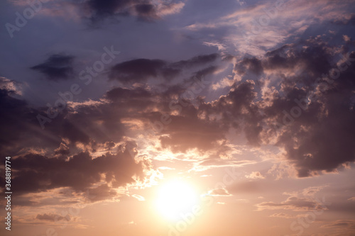 Fototapeta Naklejka Na Ścianę i Meble -  Large heavy clouds slowly float across the blue beautiful sky. Stunning landscape and view. Setting Sun Sunset in the Sky .