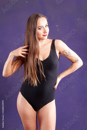 A caucasian girl, dancer, weared black body. violet background..