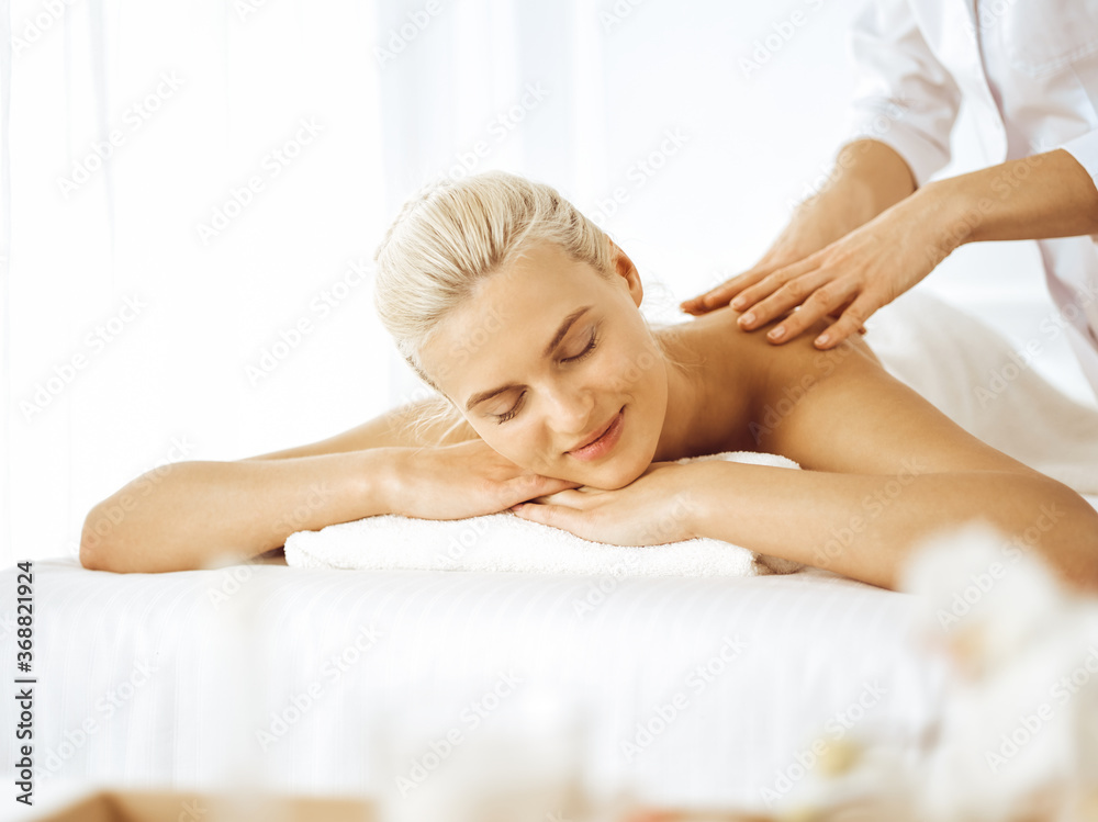 Beautiful blonde woman enjoying back massage with closed eyes. Spa salon concept Beautiful blonde woman enjoying back massage with closed eyes. Spa salon concept