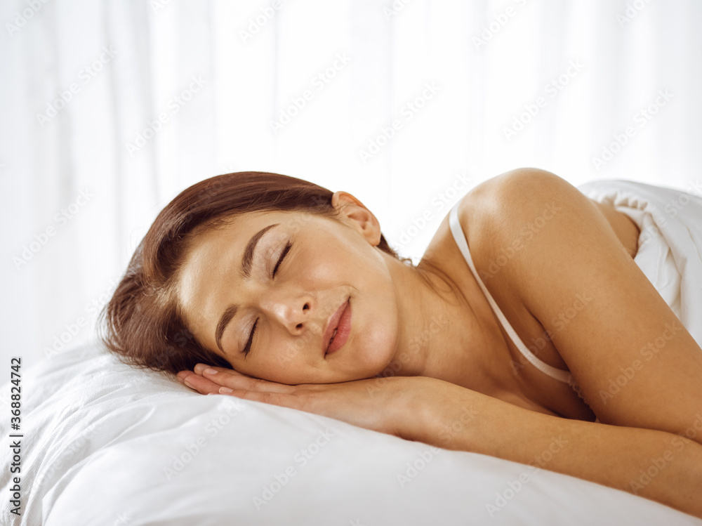 Beautiful young brunette woman sleeping while lying in bed comfortably and blissfully. Good morning concept Beautiful young brunette woman sleeping while lying in bed comfortably and blissfully. Good morning concept