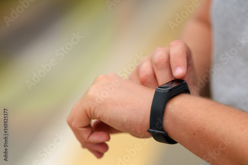 Smartwatch for fitness on the hand of a young man. He sets up the gadget to get started