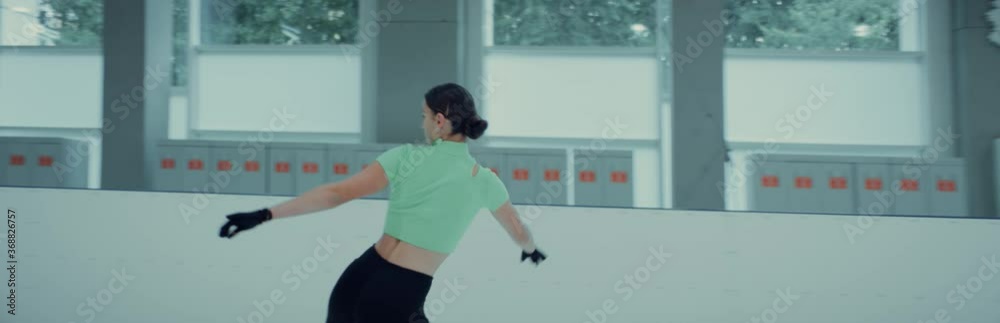 Professional teenager female ice figure skater practicing jumps on the rink. Shot on RED cinema camera with 2x Anamorphic lens, 75 FPS slow motion