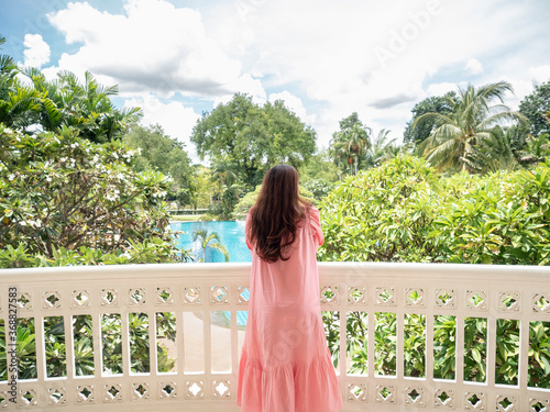 asian woman standing at vintage balcony looking away. copy space provided.