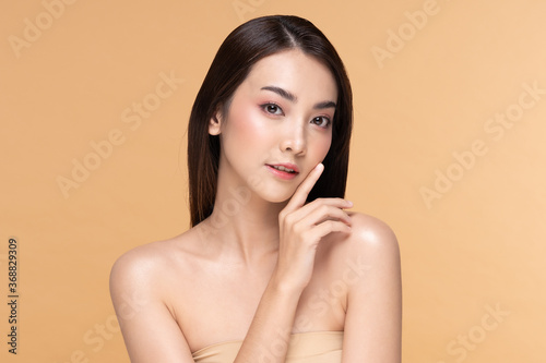 Beautiful Asian young woman touching soft cheek smile with clean fresh skin Happiness and cheerful with positive emotional,isolated on Beige background,Beauty Cosmetics and Facial treatment Concept