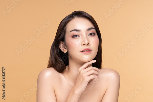 Beautiful Asian woman touching chin smile with clean and fresh skin Happiness and cheerful with positive emotional,isolated on Beige background,Beauty Cosmetics and spa Facial treatment Concept