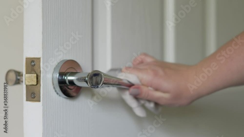 Close up of Woman cleaning door handle with an antiseptic disinfectant spray and wet wipe photo