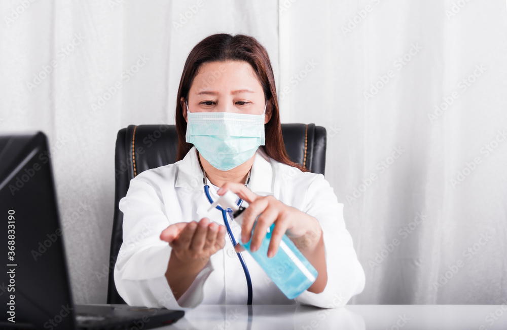 Woman doctor in white gown sitting at desk wear medical face mask